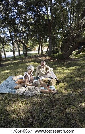 Stock Photo - Mature couple sitting on a picnic blanket in a park. Fotosearch