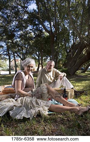 Mature couple sitting on a picnic blanket in a park View Large Photo Image Stock Photo - Mature couple sitting on a picnic blanket in a park. Fotosearch