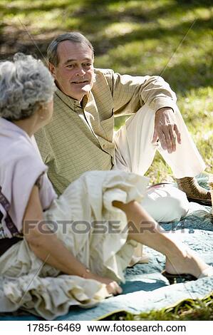 Mature couple sitting on a picnic blanket View Large Photo Image Stock Photo - Mature couple sitting on a picnic blanket. Fotosearch