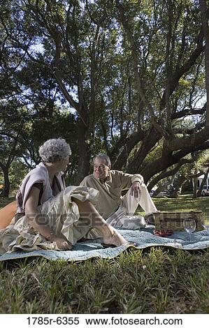 Mature couple sitting on a picnic blanket in a park View Large Photo Image Stock Photography - Mature couple sitting on a picnic blanket in a park. Fotosearch