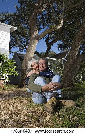 Mature couple sitting on front yard of house, surrounded by tall oak trees View Large Photo Image Stock Photo - Mature couple sitting on front yard of house, surrounded by tall oak trees. Fotosearch