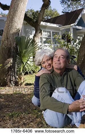 Mature couple sitting on front yard of house, surrounded by tall oak trees View Large Photo Image Stock Photograph - Mature couple sitting on front yard of house, surrounded by tall oak trees. Fotosearch
