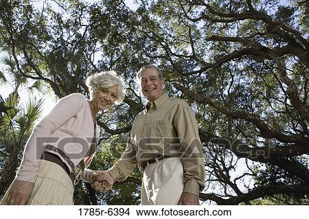 Mature couple standing together under oak trees View Large Photo Image Picture - Mature couple standing together under oak trees. Fotosearch