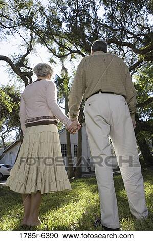Mature couple standing together under oak trees View Large Photo Image Stock Image - Mature couple standing together under oak trees. Fotosearch