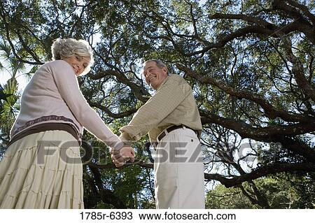 Mature couple standing together under oak trees View Large Photo Image Stock Image - Mature couple standing together under oak trees. Fotosearch