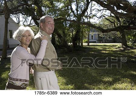 Stock Photo - Mature couple standing together under oak trees. Fotosearch