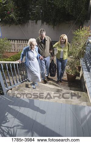 Picture - Mature couple walking with senior woman towards front of house. Fotosearch