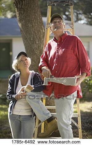 Mature couple with ladder and painting tools preparing to paint outside of house View Large Photo Image Stock Image - Mature couple with ladder and painting tools preparing to paint outside of house. Fotosearch
