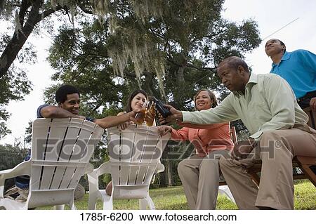 Stock Image - Mature couple with their son drinking with interracial couple in backyard. Fotosearch
