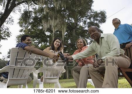 Mature couple with their son toasting drinks with inter-racial couple while sitting on lawn chairs View Large Photo Image Stock Image - Mature couple with their son toasting drinks with inter-racial couple while sitting on lawn chairs. Fotosearch