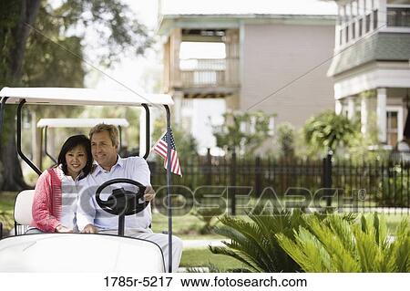 Mature inter-racial couple driving their golfcart through their neighborhood View Large Photo Image Stock Photo - Mature inter-racial couple driving their golfcart through their neighborhood. Fotosearch