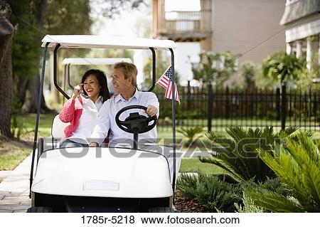 Mature inter-racial couple driving their golfcart through their neighborhood View Large Photo Image Stock Photo - Mature inter-racial couple driving their golfcart through their neighborhood. Fotosearch