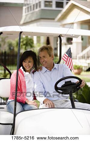 Mature inter-racial couple driving their golfcart through their neighborhood View Large Photo Image Stock Photograph - Mature inter-racial couple driving their golfcart through their neighborhood. Fotosearch