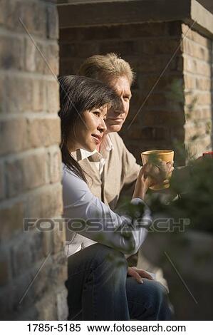 Mature inter-racial couple holding coffee mugs sitting on front steps of their house View Large Photo Image Stock Photography - Mature inter-racial couple holding coffee mugs sitting on front steps of their house. Fotosearch