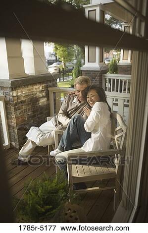 Stock Photo - Mature interracial couple sitting on front porch. Fotosearch