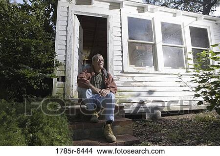 Mature man sitting on doorstep of dilapidated tool shed View Large Photo Image Picture - Mature man sitting on doorstep of dilapidated tool shed. Fotosearch