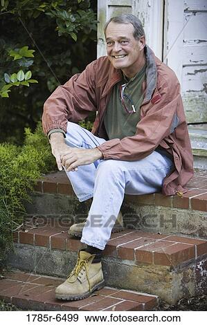 Stock Photo - Mature man sitting on doorstep. Fotosearch