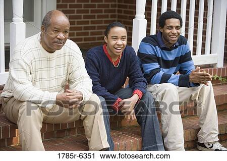 Mature man with two sons sitting on front porch of house View Large Photo Image Stock Image - Mature man with two sons sitting on front porch of house. Fotosearch