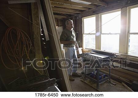 Stock Image - Mature man working with lumber and carpentry tools in tool shed. Fotosearch