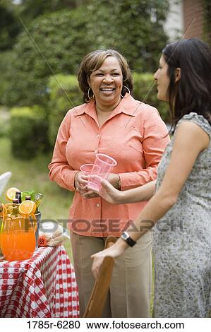 Stock Image - Mature woman conversing with younger woman at picnic. Fotosearch