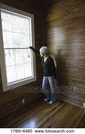 Stock Image - Mature woman gazing out window. Fotosearch