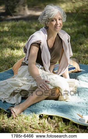 Mature woman sitting on a blanket on the grass View Large Photo Image Stock Photograph - Mature woman sitting on a blanket on the grass. Fotosearch