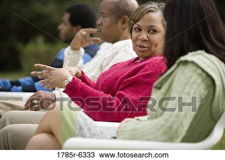Mature woman talking with family in background View Large Photo Image Stock Image - Mature woman talking with family in background. Fotosearch