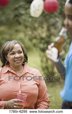 Mature woman watching son drink bottle of soda View Large Photo Image Stock Photography - Mature woman watching son drink bottle of soda. Fotosearch