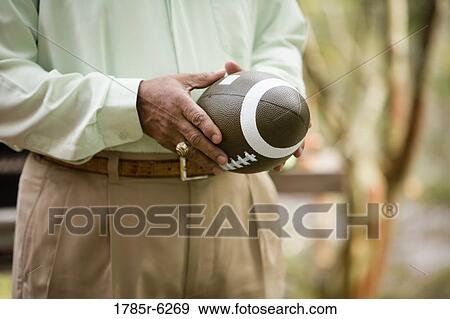 Stock Photo - Midsection of a man holding a football. Fotosearch