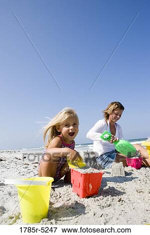 Stock Photo - Mother and daughter building sandcastles on the beach. Fotosearch