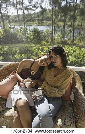 Picture - Mother and daughter sitting side by side on a chair. Fotosearch