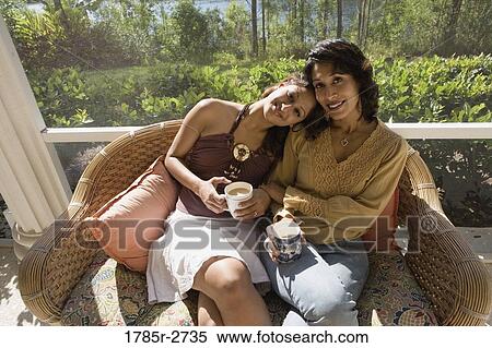 Stock Photography - Mother and daughter sitting side by side on a chair. Fotosearch