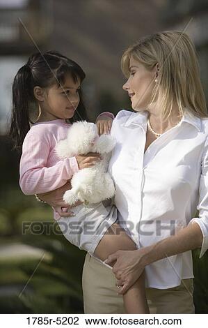 Stock Image - Mother carrying her daughter. Fotosearch