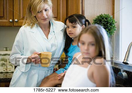Mother standing with daughters in the kitchen View Large Photo Image Stock Photo - Mother standing with daughters in the kitchen. Fotosearch
