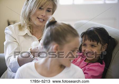 Mother with her daughters on a sofa in living room View Large Photo Image Stock Image - Mother with her daughters on a sofa in living room. Fotosearch