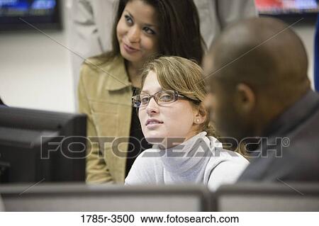 Stock Image - Office workers gathered around computer screen. Fotosearch