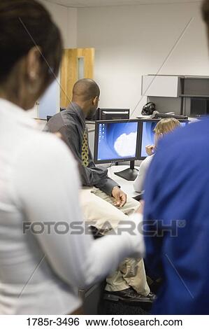 Stock Photograph - Office workers looking at computer screen. Fotosearch