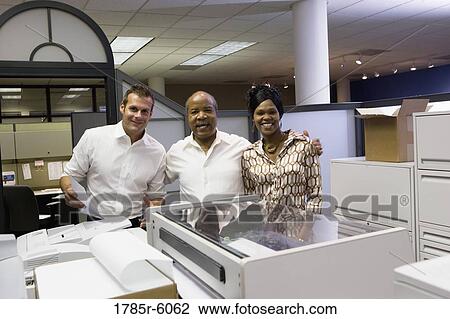 Office workers posing by office equipment View Large Photo Image Stock Image - Office workers posing by office equipment. Fotosearch