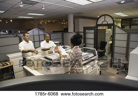 Stock Photo - Office workers talking by photocopier. Fotosearch