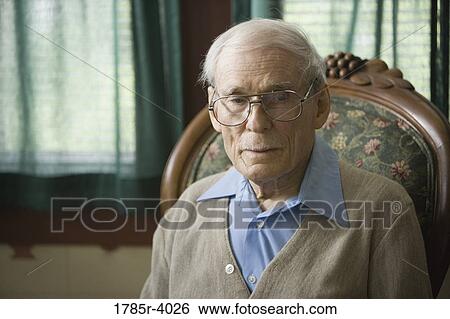 Pensive senior man sitting on a chair View Large Photo Image Stock Photograph - Pensive senior man sitting on a chair. Fotosearch