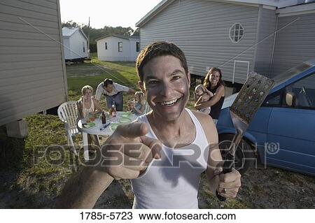 Stock Image - Portrait a blue-collar man with his family and friends in front of trailer homes. Fotosearch