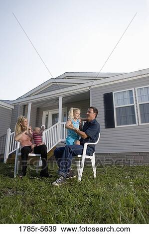 Stock Photo - Portrait of a blue-collar family sitting in front of a trailer home. Fotosearch