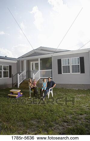 Stock Photograph - Portrait of a blue-collar family sitting in front of a trailer home. Fotosearch