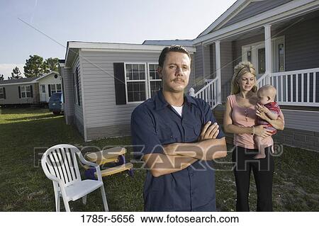 Portrait of a blue-collar man standing in front of a trailer home with wife and baby View Large Photo Image Stock Photograph - Portrait of a blue-collar man standing in front of a trailer home with wife and baby. Fotosearch