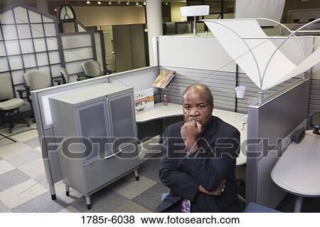 Stock Photo - Portrait of a contemplative mature businessman sitting outside office cubicle. Fotosearch