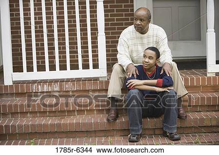 Portrait of a father and teenage son sitting on front porch of house View Large Photo Image Picture - Portrait of a father and teenage son sitting on front porch of house. Fotosearch