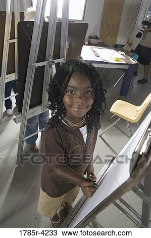 Portrait of a girl drawing on an easel in art class View Large Photo Image Stock Image - Portrait of a girl drawing on an easel in art class. Fotosearch