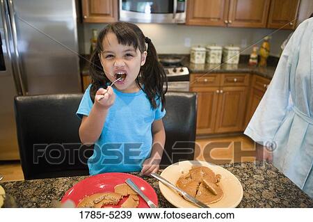 Portrait of a girl eating breakfast in the kitchen View Large Photo Image Stock Photo - Portrait of a girl eating breakfast in the kitchen. Fotosearch