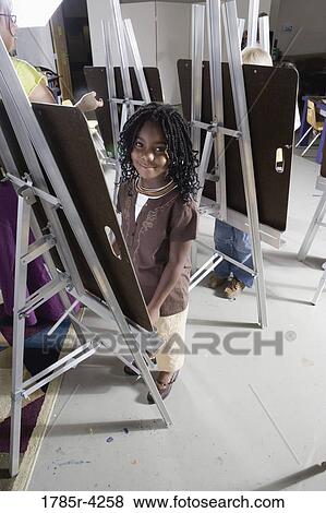 Portrait of a girl standing by a drawing easel in art class View Large Photo Image Stock Photo - Portrait of a girl standing by a drawing easel in art class. Fotosearch