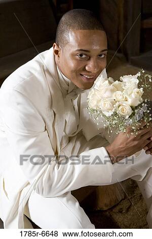 Portrait of a groom in white holding a bouquet of white roses View Large Photo Image Stock Photo - Portrait of a groom in white holding a bouquet of white roses. Fotosearch